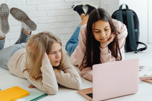 two girls looking at a laptop doing their homework for virtual school