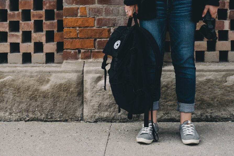 high school student wearing jeans and holding a black backpack