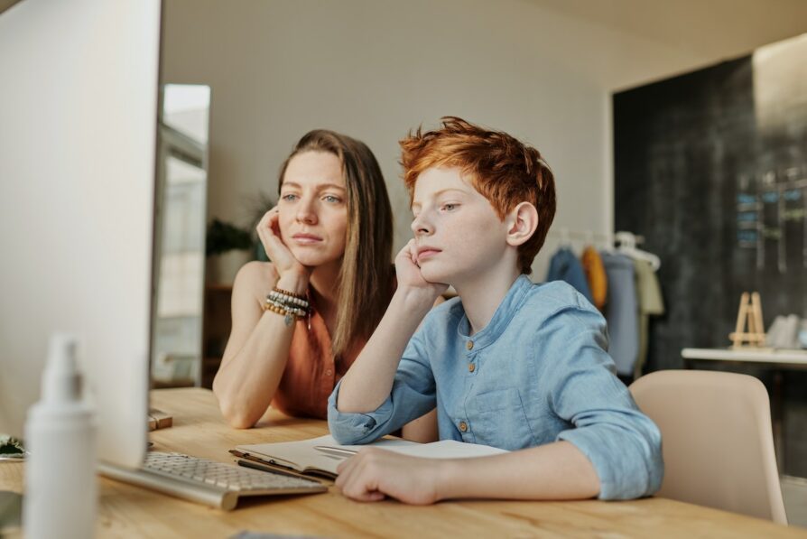male student with ginger hair and his guardian preparing for first day of virtual school