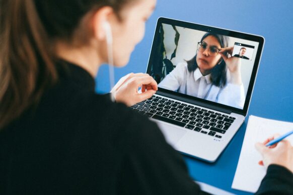 female student wearing headphones working with her teacher on the computer