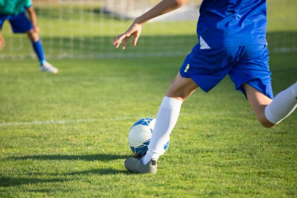 young boy wearing blue athletic wear playing soccer
