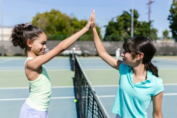 young girls high fiving after playing a match of tennis