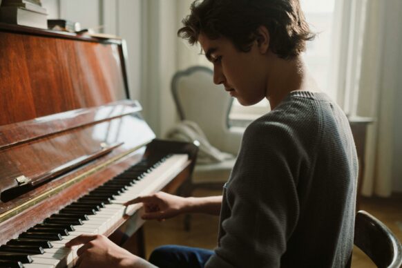 male high school student learning how to play piano