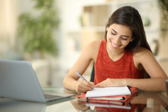 female student wearing a brick red shirt doing homework for summer school