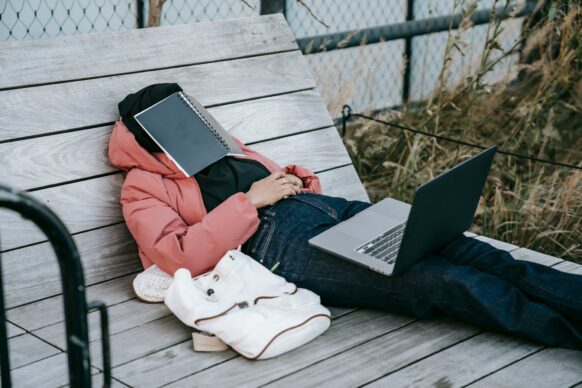 student feeling frustrated with homework and has a notebook on her face