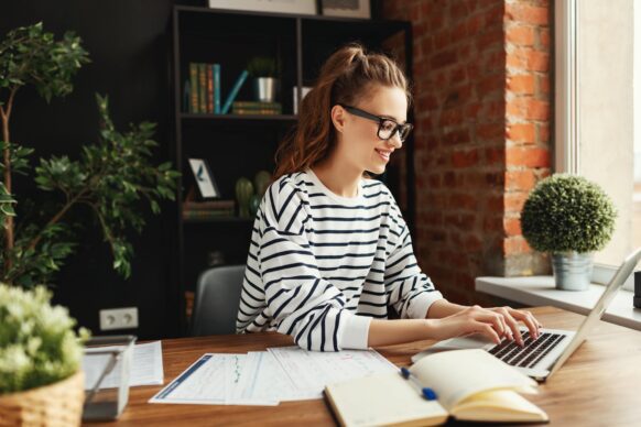 young woman wearing glasses studying at home in a room with plants