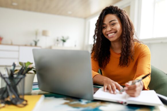 young woman smiling while studying from home in an organized room